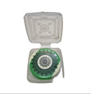 Green and white decorative item in a clear plastic case on a light gray surface with a keyboard in the background.