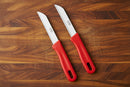 Two knives with red handles and silver blades on a cutting board
