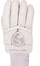 A close-up of a white cricket glove showing the back of the hand with padded finger sections and a central shield-shaped logo patch. The word 'TEST WHITE' is printed near the wrist.