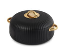 Black cookware with gold lid knob and handles on a white background